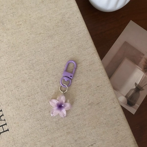 Detailed view of a purple resin flower keychain with a matching metal clasp on a book