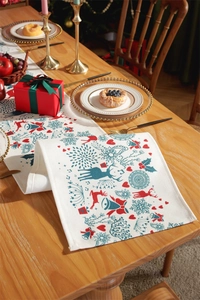 Detail of Christmas table runner featuring reindeer, bells and snowflakes on linen fabric