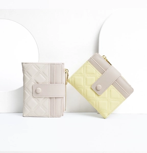 Detail of quilted PU leather wallets in beige and yellow with snap and zipper closure
