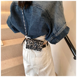Mini leopard print crossbody bag worn as a waist pouch on a denim jacket and white pants