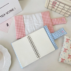 Detailed view of floral and plaid fabric book covers with button closure and coil notebook