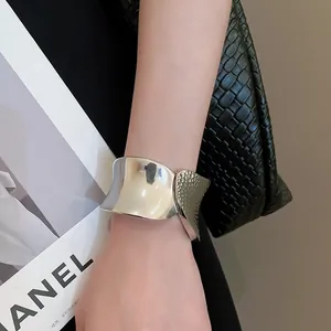 Detail of silver metallic wide cuff bracelet with hammer texture on fashion background