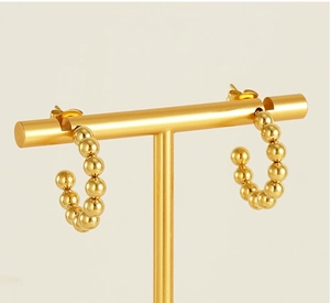 Detailed view of 18K gold-plated beaded C-shape earrings on a professional T-bar display
