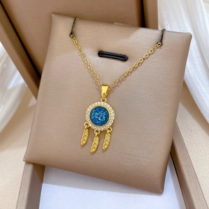 Detail of dreamcatcher necklace with blue stone, crystal accents and golden feathers
