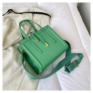 Detail view of a bright green square crossbody bag with textured fabric shoulder strap