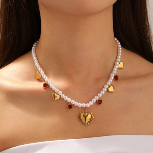 Gold plated pearl necklace with vintage heart pendants and sunburst charms on model