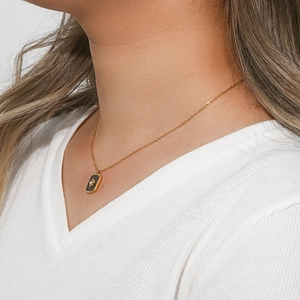 Detailed shot of a gold necklace with a black rectangular pendant featuring a star and zircon