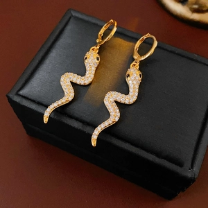 Detail shot of gold-plated snake earrings with sparkling cubic zirconia on black box