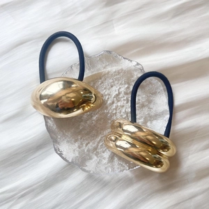 Détails d'élastiques à cheveux dorés minimalistes aux designs lisses et ondulés