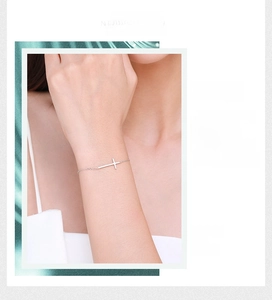 Detailed view of a minimalist S925 sterling silver cross bracelet on a woman wrist