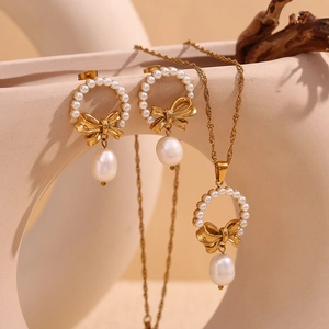 18K gold plated necklace and earrings set with pearl bow pendants on beige background