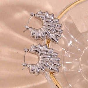 Detailed close-up of silver fan-shaped earrings with textured radial feather patterns