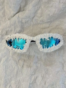 Detail view of avant-garde sunglasses with white cream texture frame and blue lenses