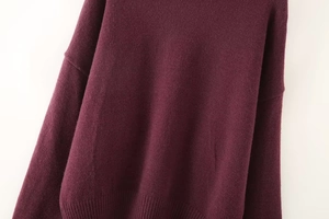 Detail of burgundy knit sweater showing soft wool texture and ribbed hem craftsmanship