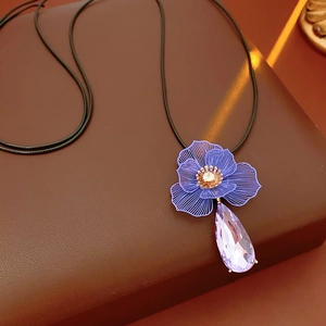 Detail of flower pendant with purple hollow design and teardrop crystal on brown leather