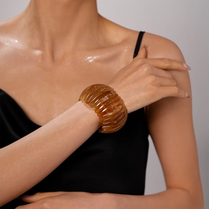 Gros plan sur un bracelet en résine ambre plissé porté au poignet au style vintage
