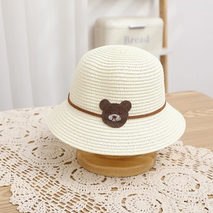 Close-up of kid's straw sun hat with cute bear patch and decorative brown string detail