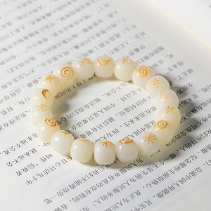Macro shot of white Bodhi root beads with golden sun and moon engravings on a book