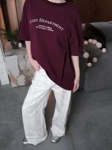 Burgundy short sleeve T-shirt with white letter print in a cozy home setting