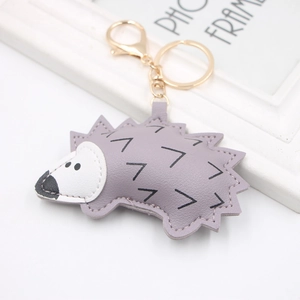 Detailed view of gray PU leather hedgehog keychain with gold metal ring on white background