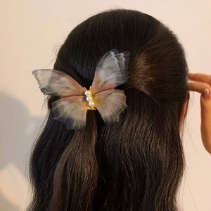Detailed view of a double-layered mesh butterfly clip with pearls on curly black hair