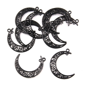 Macro shot of seven black crescent moon connectors with intricate filigree swirl patterns