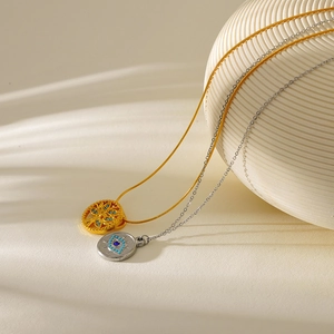 Gold tree of life and silver evil eye necklaces on elegant striped sphere decoration
