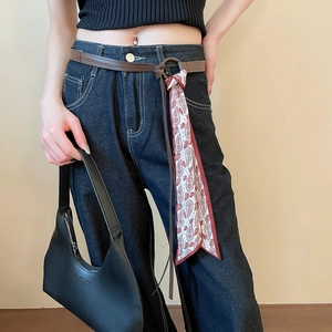 Detail of leather belt and red-white printed scarf chain on high-waist jeans