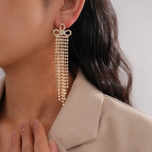 Détail de boucles d'oreilles en argent avec longues franges en strass et nœud doré élégant