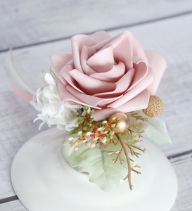 Detailed close-up of a dusty pink PE rose boutonniere with gold accents and greenery