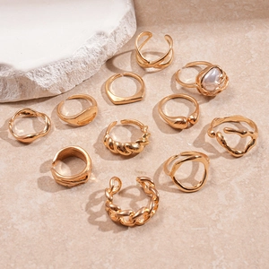 Detail view of 11-piece gold irregular geometric rings with pearls on stone background