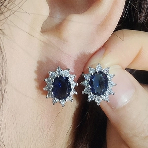 Detail showing the sunflower-inspired blue sapphire stud earrings on a model ear