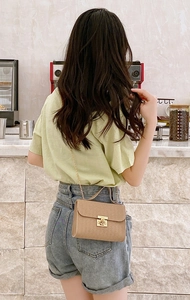 Brown textured flap crossbody bag with gold chain strap shown in a cozy cafe setting