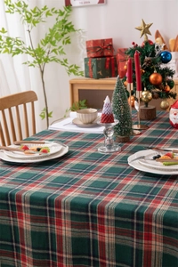 Detail of red and green plaid Christmas tablecloth with festive fringe on a wooden table