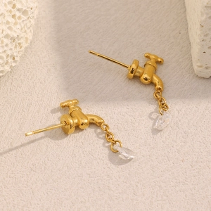 Macro detail of gold faucet earrings with a clear water drop stone on textured stone base