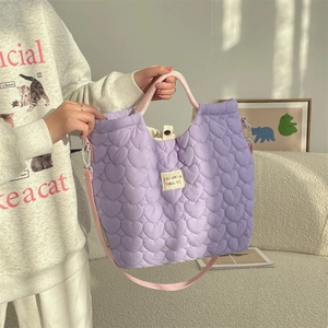 Détail du sac cabas matelassé à cœurs violets avec bandoulière rose et étiquette tissée