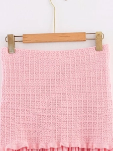 Close-up of pink knit dress set texture showing intricate stitching on a wooden hanger
