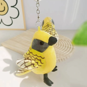 Detail of yellow plush bird keychain with intricate brown and white wing embroidery