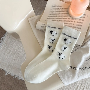 Close-up of knit cream mid-tube socks featuring a cute 3D plush sheep design and text