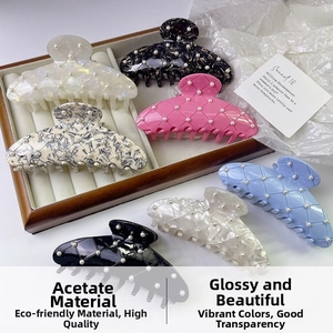 Macro detail of acetate shark hair clips with pearl inlay in various colors on a tray