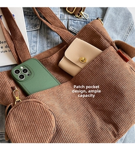 Detail view of brown corduroy tote bag showing front pocket and mini round coin purse charm