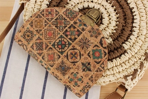 Close-up of circular straw bag with cork flap featuring vintage mosaic patterns