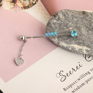 Macro detail of silver industrial barbell with blue stones and sparkling heart pendant