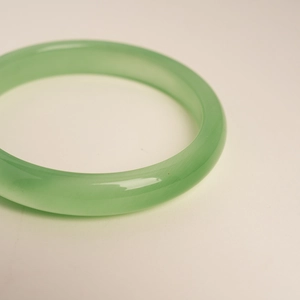 Macro shot of light green translucent cat eye stone bangle with smooth polished surface