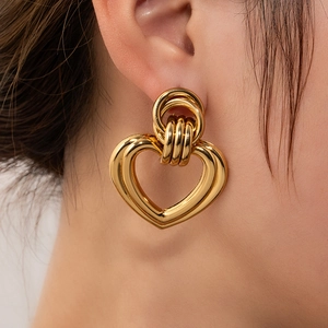 Close-up of oversized gold heart earrings with polished finish on model's ear