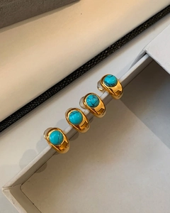 Detailed close-up of 18k gold plated turquoise stud earrings on a white jewelry box display