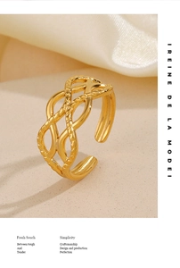 Vue détaillée de la bague entrelacée dorée sur texture sable et tissu en soie