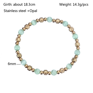 Detail of 6mm opal and patterned gold stainless steel beaded bracelet on white background