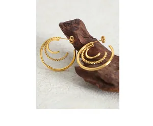 Detailed macro view of 18K gold-plated C-shape earrings with layered twisted rope texture