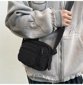 Close-up of black denim crossbody bag with adjustable strap and multiple front pockets